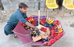 A vendor arranging and displaying children's shoes to attract the customers at Lahori Mohalla Road