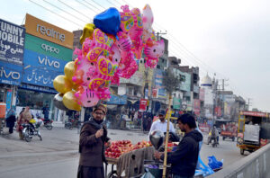 A customer purchasing gas balloons for his children from a vendor at Shahdara Market.