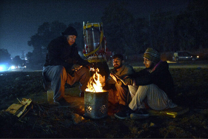 A group of people sitting around a crackling wood fire, seeking warmth and comfort as the winter chill envelops the Provincial Capital