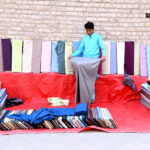 A vendor arranging and displaying cloth to attract the customers at old Bus Stand Road