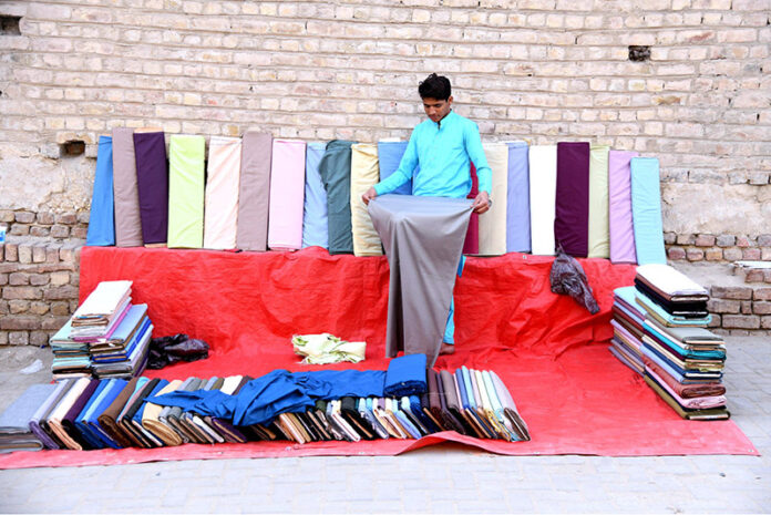 A vendor arranging and displaying cloth to attract the customers at old Bus Stand Road