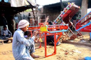 Laborers paint vehicle iron frames in their workshop.