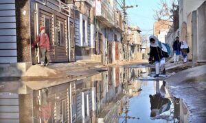 Students facing difficulties while passing through sewerage water accumulated in a street of Tiwana Park.