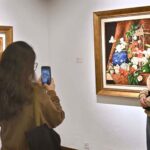 A visitor capturing picture with the on displayed artwork at exhibition “A Spring Reverie - Petals & Porcelain” by talented still life artist, Irfan Cheema in Tanzara Gallery