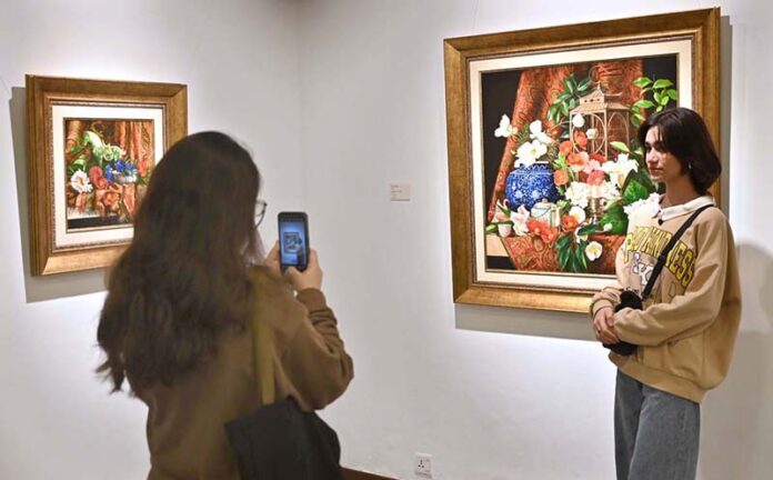 A visitor capturing picture with the on displayed artwork at exhibition “A Spring Reverie - Petals & Porcelain” by talented still life artist, Irfan Cheema in Tanzara Gallery
