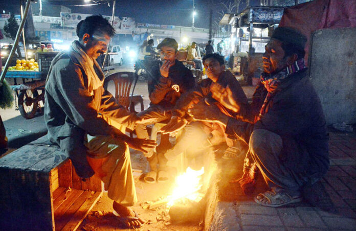 A group of people huddle around a crackling wood fire, finding warmth and comfort as the winter chill takes hold in city