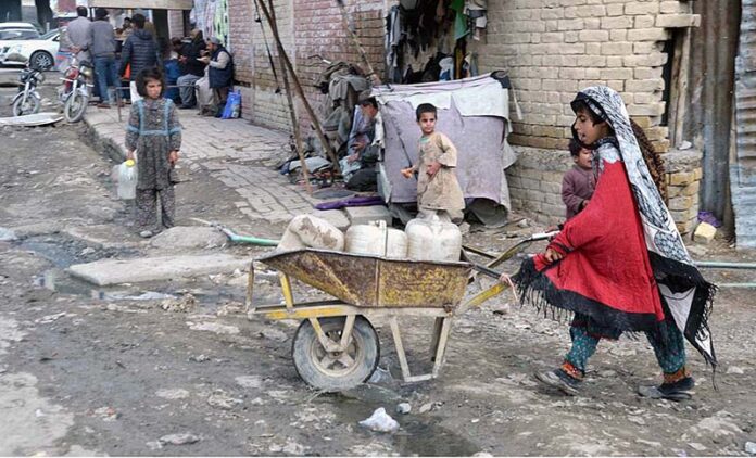 A small girl pushing a wheelbarrow to fetch water for home at Pishin Stop