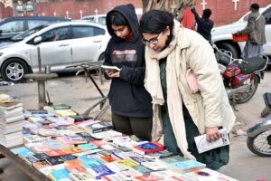Women busy in selecting and purchasing old books from roadside stall at Mall Road
