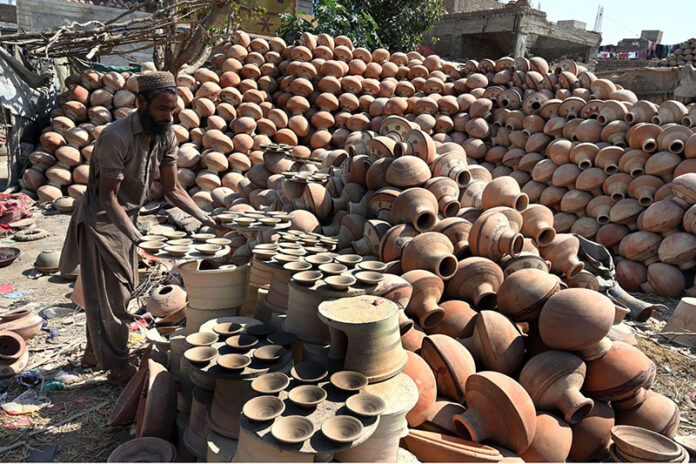 A worker arranging clay-made stuff for drying purpose at his work place at Kumharpara