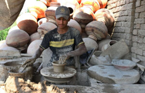 A worker arranging clay-made stuff for drying purpose at his work place at Kumharpara