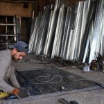 A welder diligently works on an iron gate at his workshop near Dhoke Kala Khan