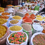 A vendor displays aromatic spices with rich colors and grocery essentials at his shop in Royal Bazaar