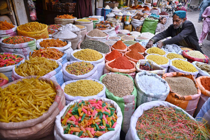 A vendor displays aromatic spices with rich colors and grocery essentials at his shop in Royal Bazaar