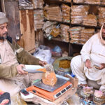 A vendor weighs and sells roasted chickpeas and other popular snacks at his shop in Shahi Bazaar
