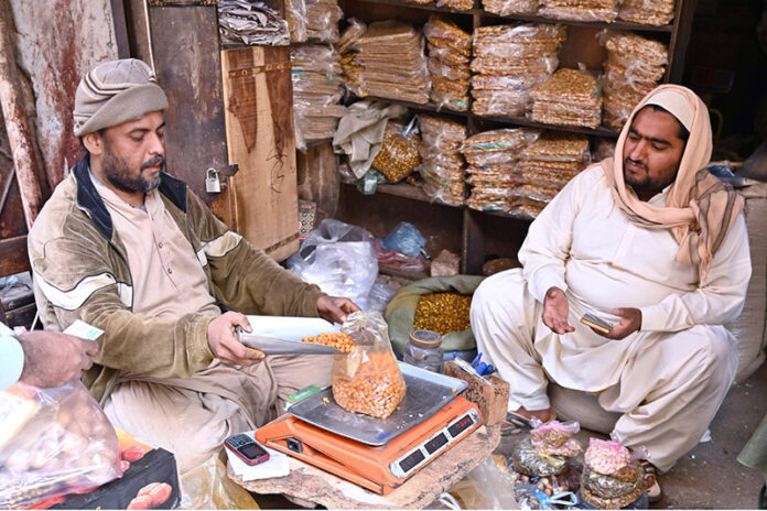 A vendor weighs and sells roasted chickpeas and other popular snacks at his shop in Shahi Bazaar