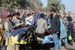 People selecting and purchasing second-hand coats from a roadside cart vendor