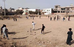 Youngsters are playing cricket in the local ground at Qasim Park