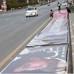 Laborers diligently prepare banners for display on a bridge along the Expressway ahead of Kashmir Solidarity Day
