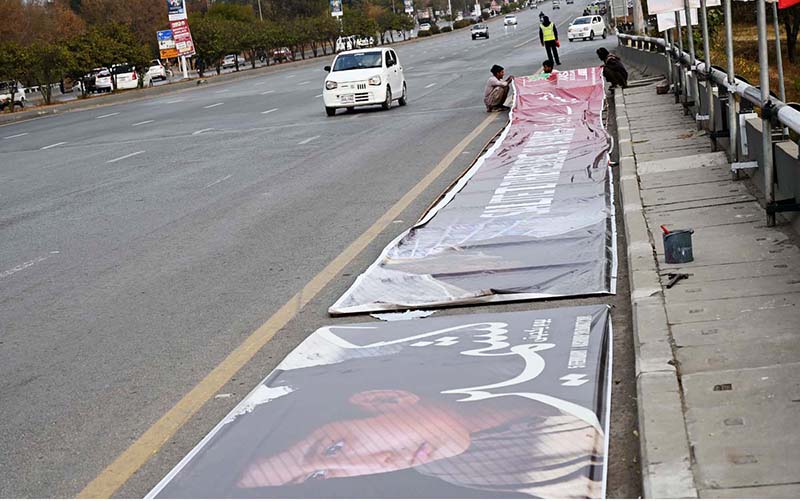 Laborers diligently prepare banners for display on a bridge along the Expressway ahead of Kashmir Solidarity Day