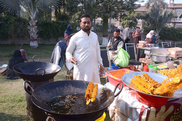 A vendor fries crispy potato spring chips for customers at his roadside stall in the city