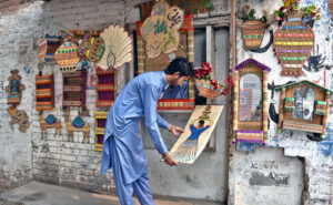 An artist attracts customers by pasting various artworks made of bamboo sticks on the wall of his shop.