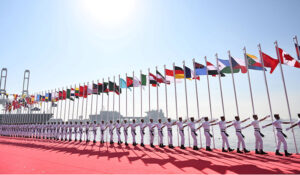 Pakistani Navy personnel carry the flags of participating foreign countries during the flag-hoisting ceremony of AMAN 2025 in provincial capital