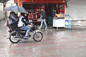 An aged man pushes a handcart with popcorn walks in rain to find customers.