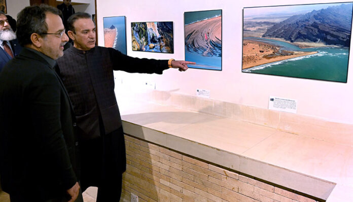 Federal Minister of Energy Sardar Awais Ahmed Khan Leghari is briefed by the organizer about the stunning landscape photographs of Balochistan at the launch of a coffee table book and large-format photo exhibition in the federal capital