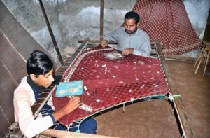 Workers are busy embroidery work on dresses at their workplace.