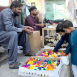Children are buying colorful chicks from a vendor at a roadside setup