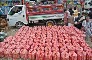 A labourer busy in off load fresh carrots from a delivery truck at vegetable market.
