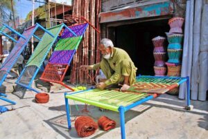 An artisan knitting charpai on roadside in city earn his livelihood.