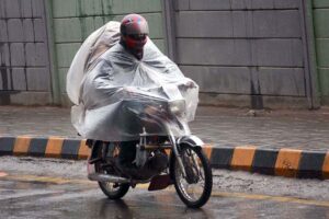A motorcyclist on the way under the cover of plastic sheet to protect from rain that experienced in the Provincial Capital.