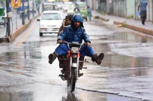 A motorcyclist on the way under the cover of plastic sheet to protect from rain that experienced in the Provincial Capital.