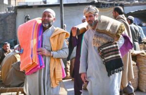 Vendors carry and sell towels and warm shawls over their shoulders to attract potential buyers for the winter needs of the locals at Gur Mandi.