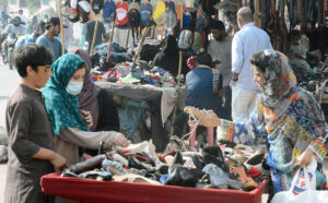 Women browse a variety of used shoes and looking for cheaper footwear options at a stall in Saddar.