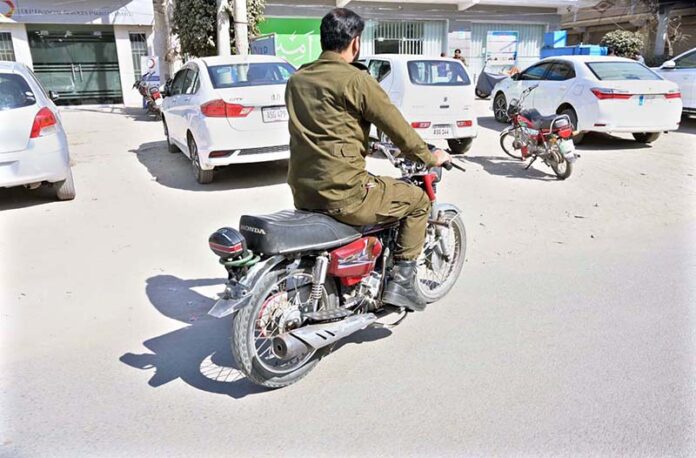A police official is riding a motorcycle without a number plate and without wearing a safety helmet near the DPO office on Katchery Road. This is a clear violation of traffic rules and requires the immediate attention of the concerned authorities