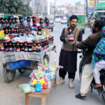 A man buys dolls for children from a vendor along the roadside