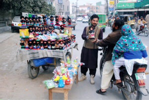 A man buys dolls for children from a vendor along the roadside