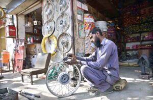 A mechanic busy in polishes a motorcycle wheel rim at his workshop