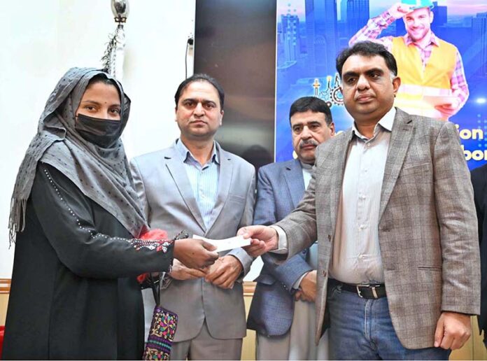 Chairman Pakistan Surgical Association Zeeshan Tariq Sheikh distributes cheques among workers during a Labour Department cheque distribution ceremony at SIMAP