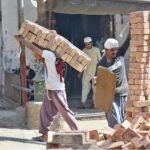 Labourers busy in shifting the bricks for construction work of home at Fort Road area