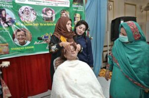 A makeup artist demonstrates expert techniques to train students during a workshop at an event organized by the Mashallah Beautification College of Art.