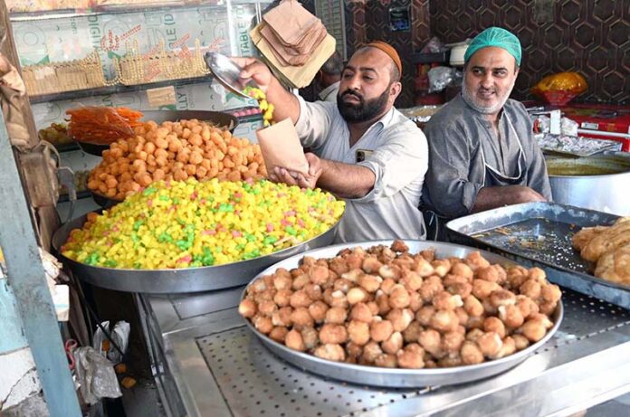 A halwai seller sells sweets in Gwalmandi Bazaar on the occasion of Shab Barat