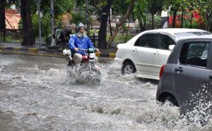 A motorcyclist wears rain suit to protect him from rain and cold on his way during the first rain of the season in the provincial capital.