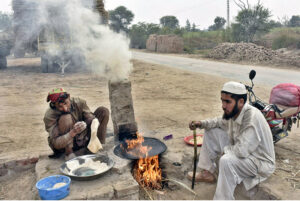 Daily wage laborers cook bread on a wooden stove near Ravi Road.