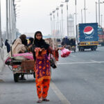 A young girl selling meat as people purchase for throwing for birds as mercy on the bridge at River Ravi