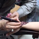 Artisan applies henna to girls' hands as they prepare for Eid ul Fitr celebrations