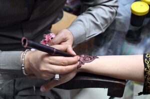 Artisan applies henna to girls' hands as they prepare for Eid ul Fitr celebrations