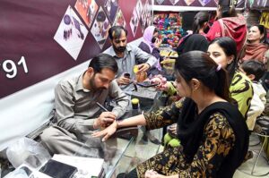 Artisan applies henna to girls' hands as they prepare for Eid ul Fitr celebrations